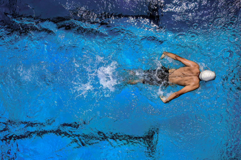 Person mit Badekappe in einem Schwimmbad, von oben fotografiert