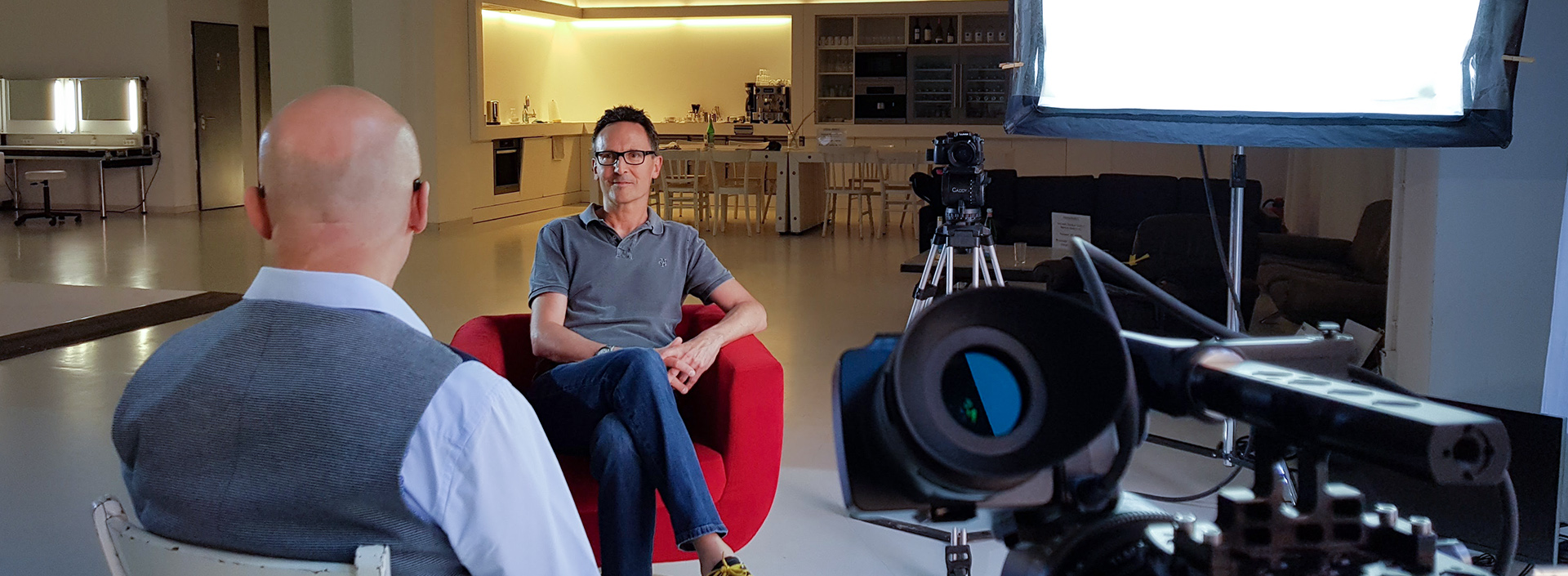 Andreas Dirksen sitzt in einem Fotostudio im Roten Sessel für ein Interview