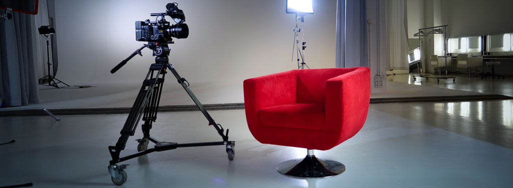 Der Rote Sessel und eine Kamera auf Stativ in einem Fotostudio-Set mit Lichtern