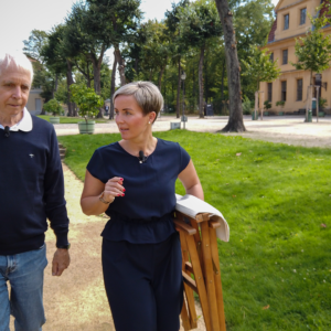 Zwei Personen mit Klappstuhl laufen im Park Berlin Charlottenburg