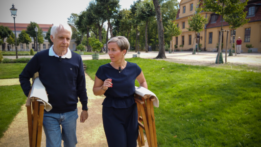Zwei Personen mit Klappstuhl laufen im Park Berlin Charlottenburg