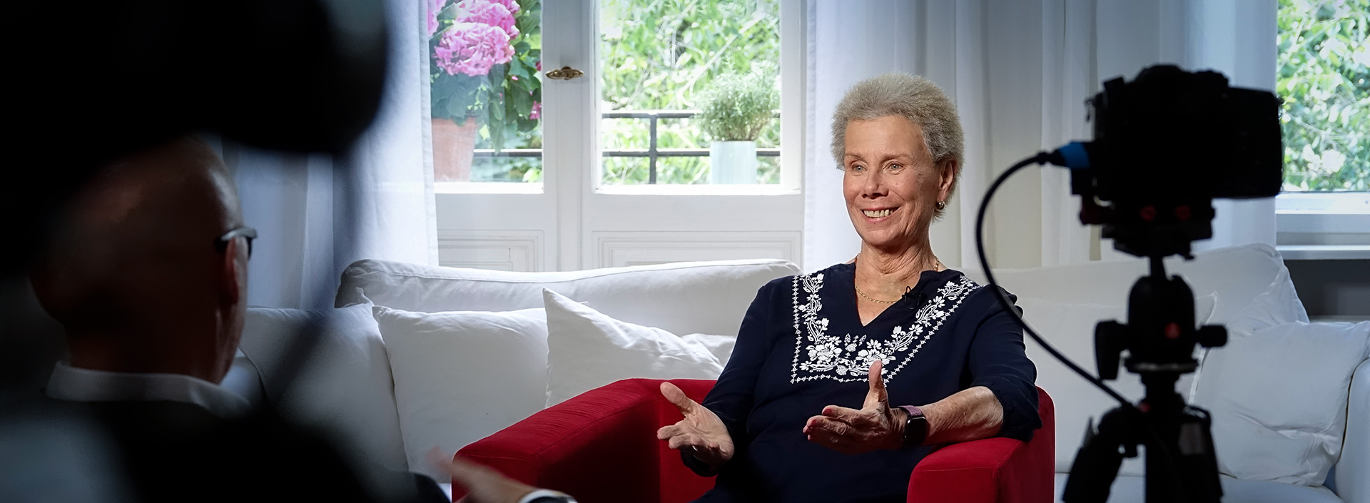 Susanne Kranz sitzt vor einem Fenster im Roten Sessel für ein Interview