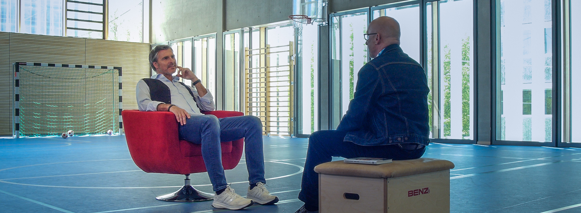 Uli Roth sitzt in einer Sporthalle im Roten Sessel für ein Interview