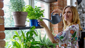Andrea Röhm steht am Küchenfenster und gießt ihre Kräuter