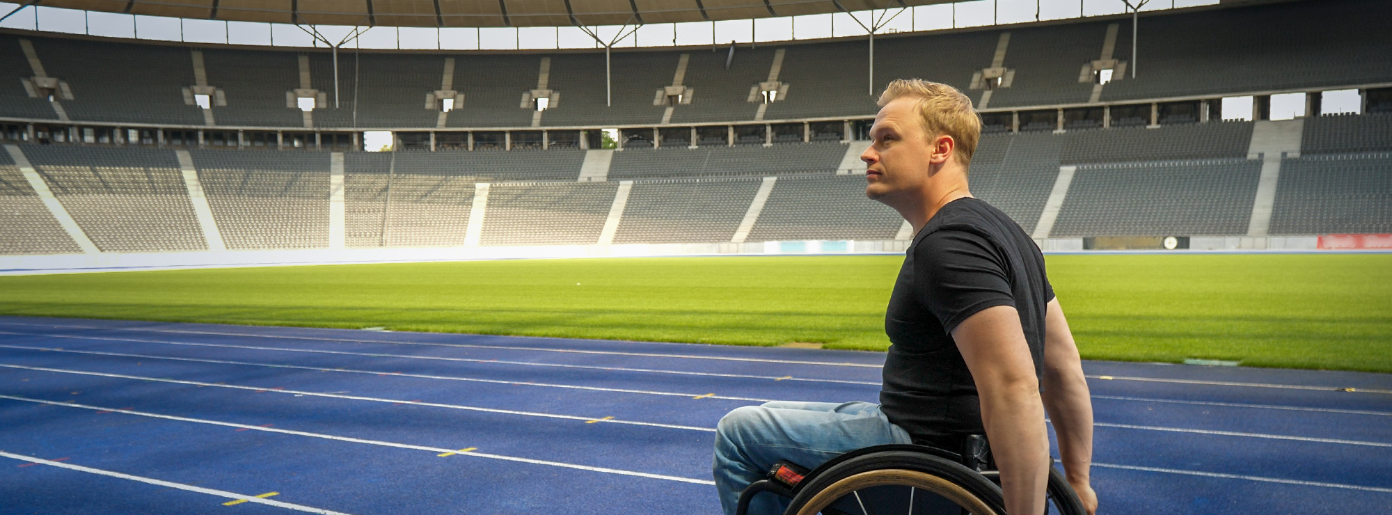 Benjamin Lenatz fährt mit seinem Rollstuhl über die blaue Laufbahn im Olympiastadion Berlin