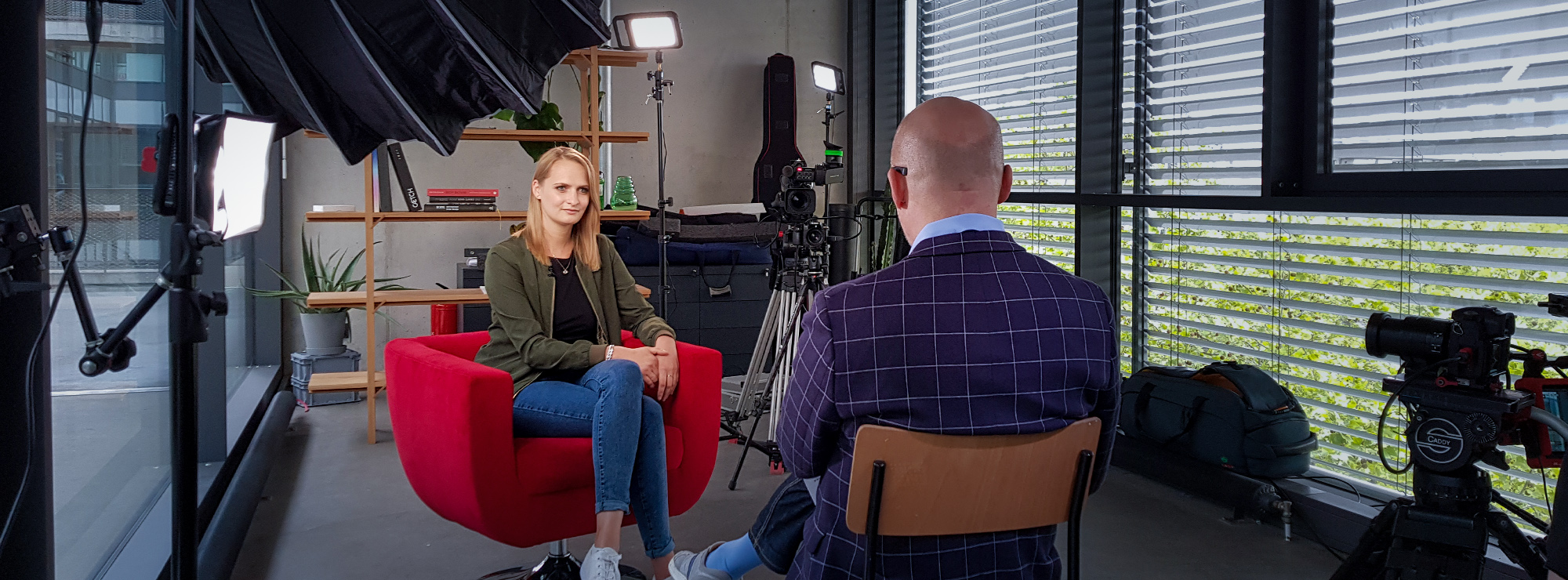 Marieke Steiner beim Interview im Roten Sessel in einem modernen und minimalistischen Büro, umgeben von Licht und Kameras