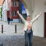 Frau in einer Altstadt als Tourist reißt die Hände nach oben
