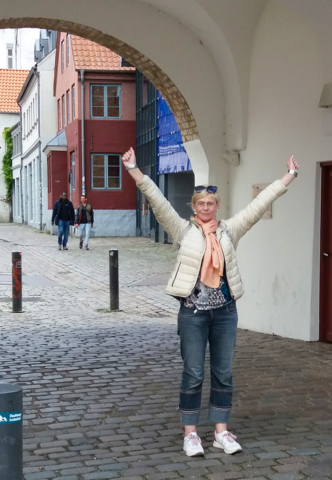 Frau in einer Altstadt als Tourist reißt die Hände nach oben