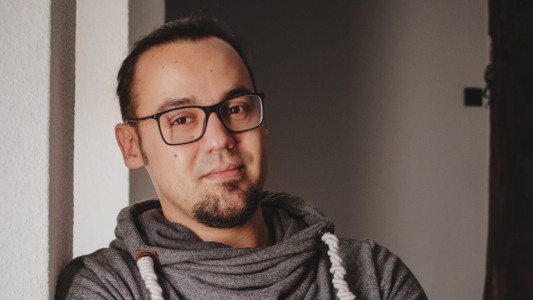 Domenic Wenz lehnt an einer Wand und blickt in die Kamera