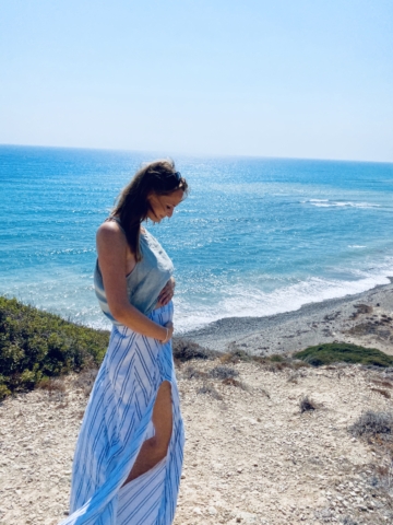 Schwangere Frau am Strand hält ihren Bauch