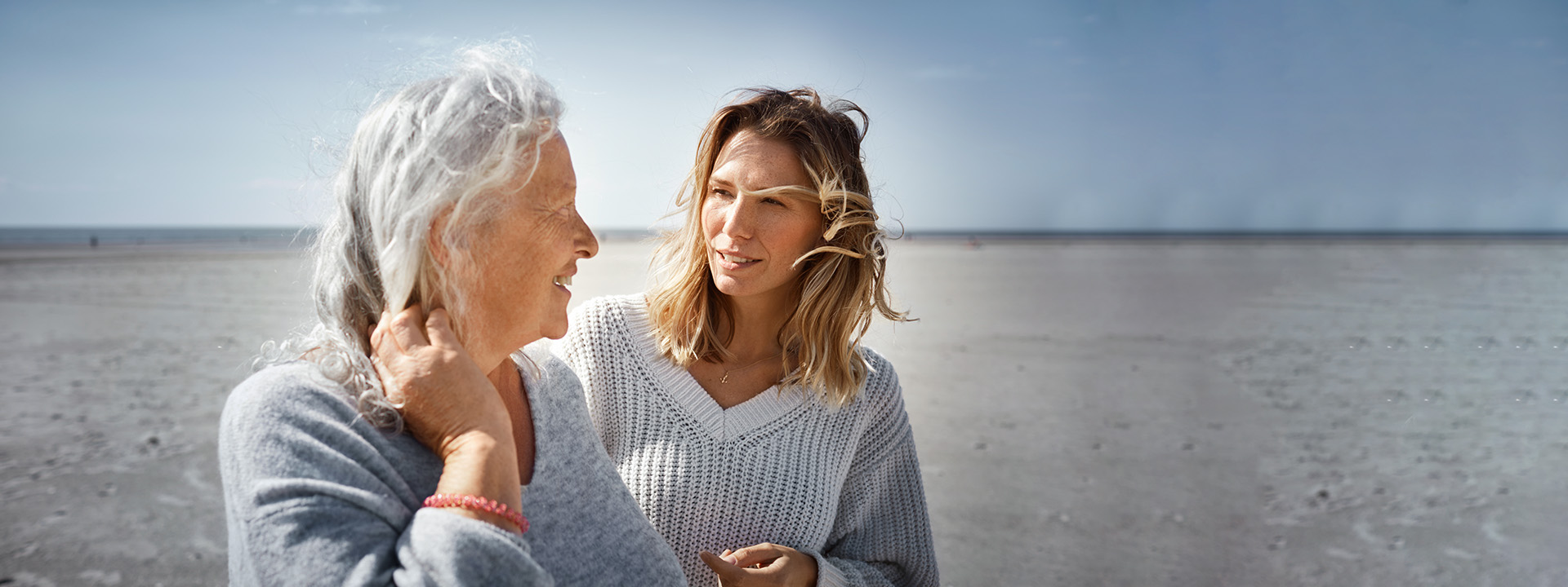 Ältere Frau im Gespräch mit erwachsener Tochter am Strand